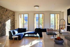 a living room with a blue couch and windows at La myrtillette in Luchon