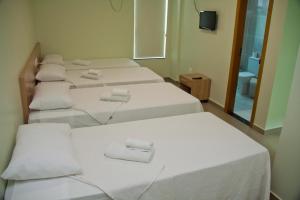 a group of four beds in a room at HC Hotel Paraopeba in Paraopeba
