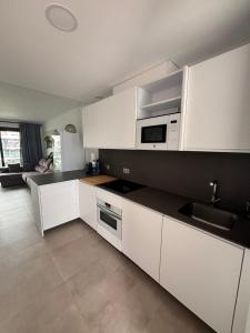 a kitchen with white cabinets and a sink and microwave at VillaBarrosa Boutique, Ático en Zahara de los Atunes in Zahara de los Atunes