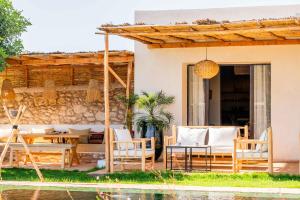 a patio with a table and chairs by a pool at Villa Yakout in Ghazoua