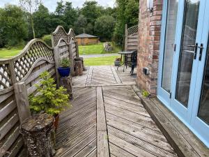 ein Holzdeck mit einer Bank neben einer Tür in der Unterkunft Maes Y Grove Cottage in Llanddarog