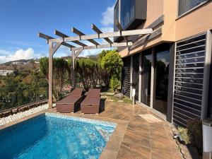 a swimming pool with a wooden pergola next to a house at Unique suite piscine vue mer in Faaa