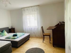 a bedroom with a bed and a desk and a window at Ferienwohnung Heilmanns Hof in Hausen