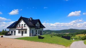 a white house with a black roof on a hill at Zasankowe Wzgórze in Zasań
