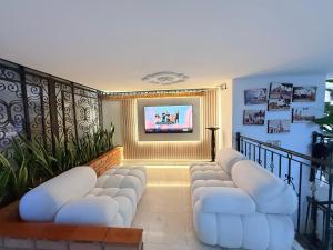 a living room with white chairs and a flat screen tv at Hotel Santa Sofia in Bucaramanga
