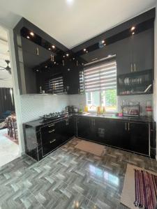 a kitchen with black cabinets and a tile floor at D Aur Poolvilla Seaview in Bachok