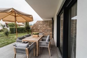 a wooden table with chairs and an umbrella on a patio at Bay 12° Boutique Apartment am Chiemsee in Übersee
