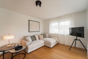 a white living room with a couch and a tv at Bay 12° Boutique Apartment am Chiemsee in Übersee