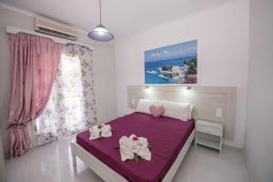 a bedroom with a purple bed with two dolls on it at Villa Eleni Holidays Resort up to 18 guests in Karousádes