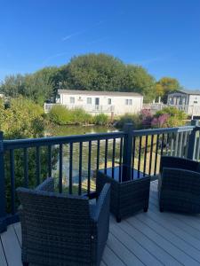 a deck with two chairs and a view of a river at DJD ,Country Style Luxury Lodge, Manor Park Sleeps 4 in Hunstanton