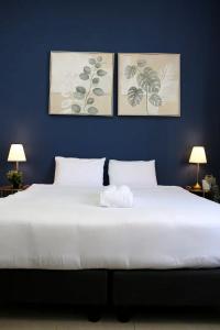 a bedroom with a large white bed with three pictures on the wall at Paris Square Apartments Downtown in Haifa