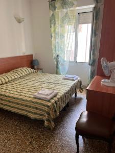 a bedroom with a bed and a chair and a window at Hotel Washington in Sanremo