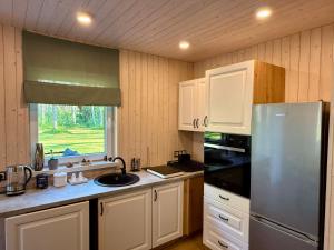 a kitchen with white cabinets and a stainless steel refrigerator at Viesu māja Silapurenes in Mērsrags +9 photos