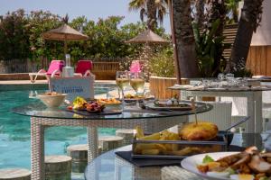 a table with plates of food next to a swimming pool at Grand Hôtel Les Flamants Roses Thalasso & Spa in Canet-en-Roussillon