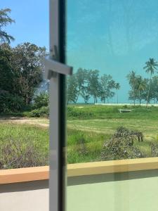 a window with a view of a field of grass at D Aur Poolvilla Seaview in Bachok