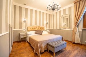 a bedroom with a bed and a chair and a chandelier at Boutique Hotel Masolino in Panicale