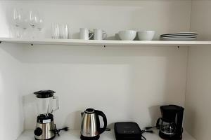Un estante con tazas y electrodomésticos en la encimera de la cocina. en Apto central com cama hospitalar, en Londrina