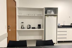 Una cocina con gabinetes blancos y un refrigerador. en Apto central com cama hospitalar, en Londrina 9 fotos más