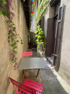 deux chaises rouges et une table en bois dans une ruelle dans l'établissement Appartement avec Patio, à Carcassonne