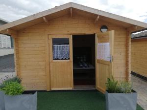 a wooden shed with a door and two plants at AlmOtel - Auf der HerziAlm 