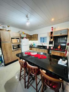 a kitchen with a black table and wooden cabinets at Casa próximo à praia Canasvieiras e ingleses in Florianópolis