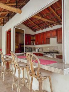 a kitchen with wooden cabinets and a counter with chairs at Escapada a Perla de Mar - ATAMI in Tamanique