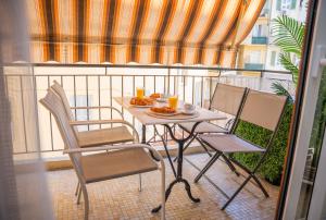 a table and chairs on a balcony with orange juice at Appartement Spacieux au Port de Nice avec Clim et Parking Gratuit in Nice