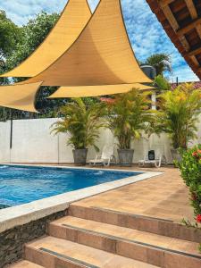 a swimming pool with a large yellow umbrella over it at Escapada a Perla de Mar - ATAMI in Tamanique