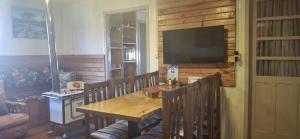 a dining room with a table and a flat screen tv at Quintal das Araucárias hospedagem in São Joaquim