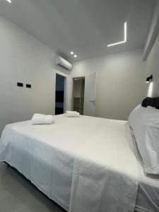 a white bedroom with a large bed with white sheets at Maison Miry in Rapallo