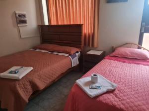two beds in a room with towels and a cup on the bed at Hostal La Extincion in Torotoro