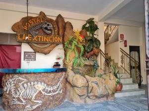 a lobby with a large rock wall with a dinosaur display at Hostal La Extincion in Torotoro
