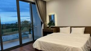a bedroom with a white bed and a large window at Happy Ocean View Villa in Tài Xá