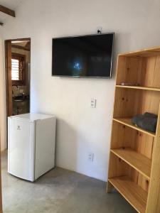 a room with a refrigerator and a television on a wall at Suite Jenipapo Caraiva in Caraíva