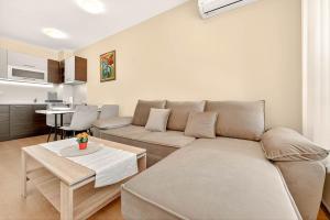 una sala de estar con un sofá y una mesa en Апартамент Danili нов двустаен апартамент с басейн и паркомясто в гр Бяла, en Byala