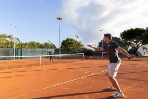 a man holding a tennis racket on a tennis court at Invisa Hotel Club Cala Verde in Es Figueral Beach
