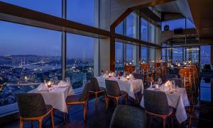 a restaurant with white tables and chairs and windows at Renaissance Istanbul Polat Bosphorus Hotel in Istanbul