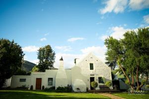 a white house with a hill in the background at Oue Werf Country House in Oudtshoorn