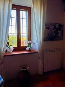 a window with white curtains in a room at Tenuta di Freddano in Osa