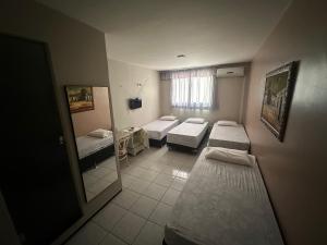 a small room with two beds and a mirror at Horto Hotel in Juazeiro do Norte