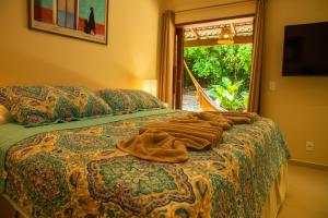 a bedroom with a bed with a blanket and a window at Forest House Pipa in Pipa