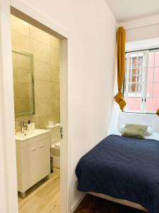 a bedroom with a bed and a bathroom with a sink at Sao Pedro Guest House in Faro