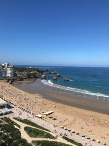 ein Strand mit vielen Menschen und das Meer in der Unterkunft Beau studio rénové, balcon, accès plage, piscine in Biarritz