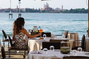 a woman sitting at a table with a drink at San Clemente Palace Venice in Venice +64 photos