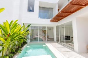 een binnenzwembad in een huis met glazen wanden bij White Palm Villa in Canggu