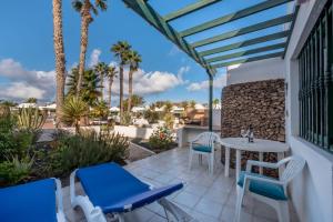 Un patio con mesa y sillas y palmeras. en Jardin Del Sol 30, en Playa Blanca