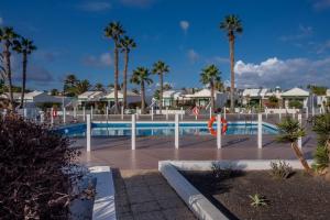 una piscina en un complejo con palmeras y casas en Jardin Del Sol 30, en Playa Blanca
