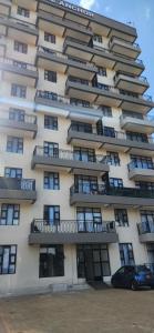a tall building with balconies and a car parked in front at Keshi homes ruaka in Kiambu