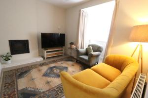 a living room with a yellow couch and a television at No 26 Town House in Killarney