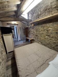 Un dormitorio con una cama en una pared de piedra. en Il nido di Matilde, en Rossena